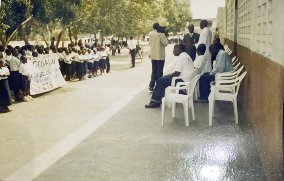 Élèves en uniforme alignés dans la cour lors d'une distribution de manuels scolaires organisée par le CEDALU